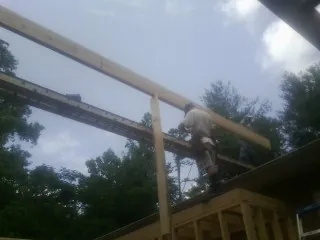 Carpenter setting a ridge beam over a new addition frame — Ice Dam Removal by Roofing Brothers in Barto
