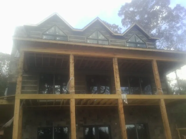 Dormers and porch framing on a large log home under construction — Roof Coating work by our crew in Barto