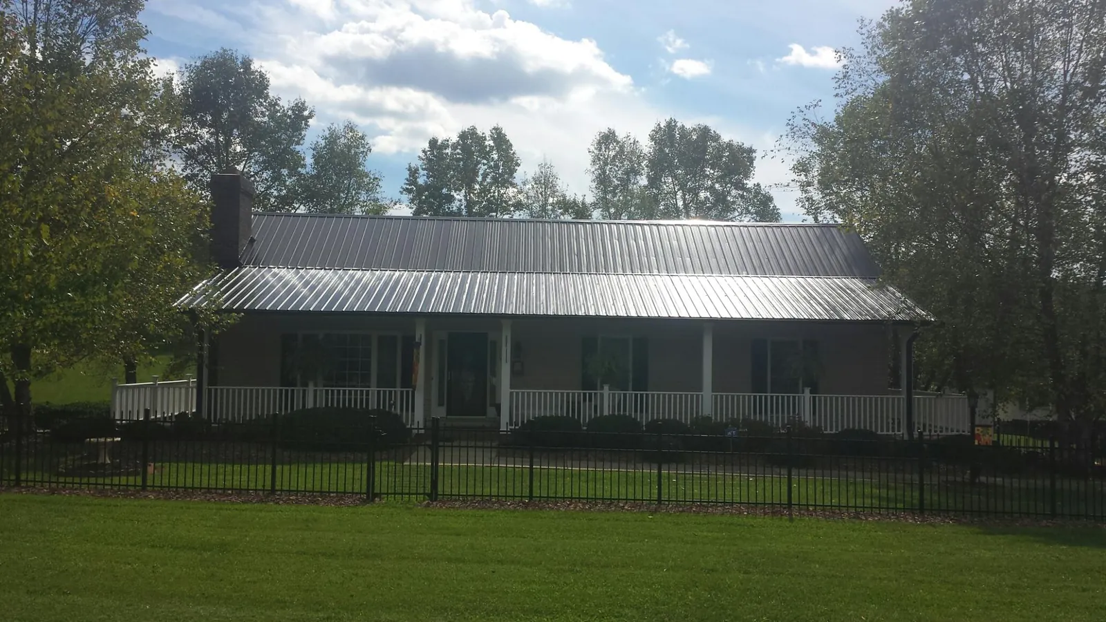 Gray metal roof on a brick ranch with a full width front porch — Gutter Guard Installation work by our crew in Barto