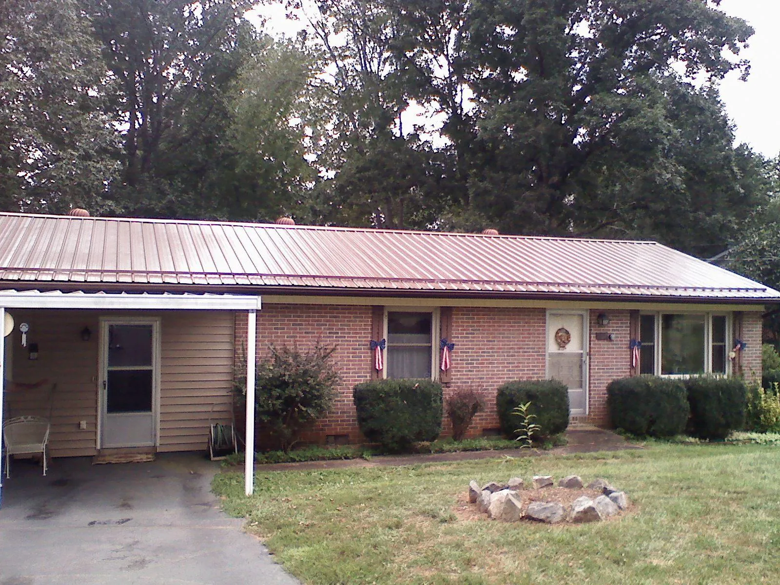 Bronze metal roof and carport on a brick ranch home — Roof Repair work by our crew in Barto